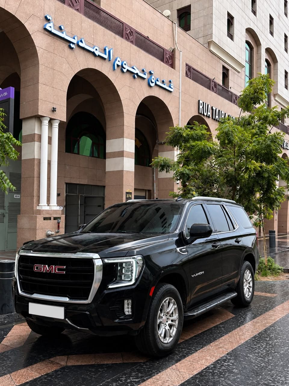 A black GMC Yukon waiting outside a hotel in Madinah